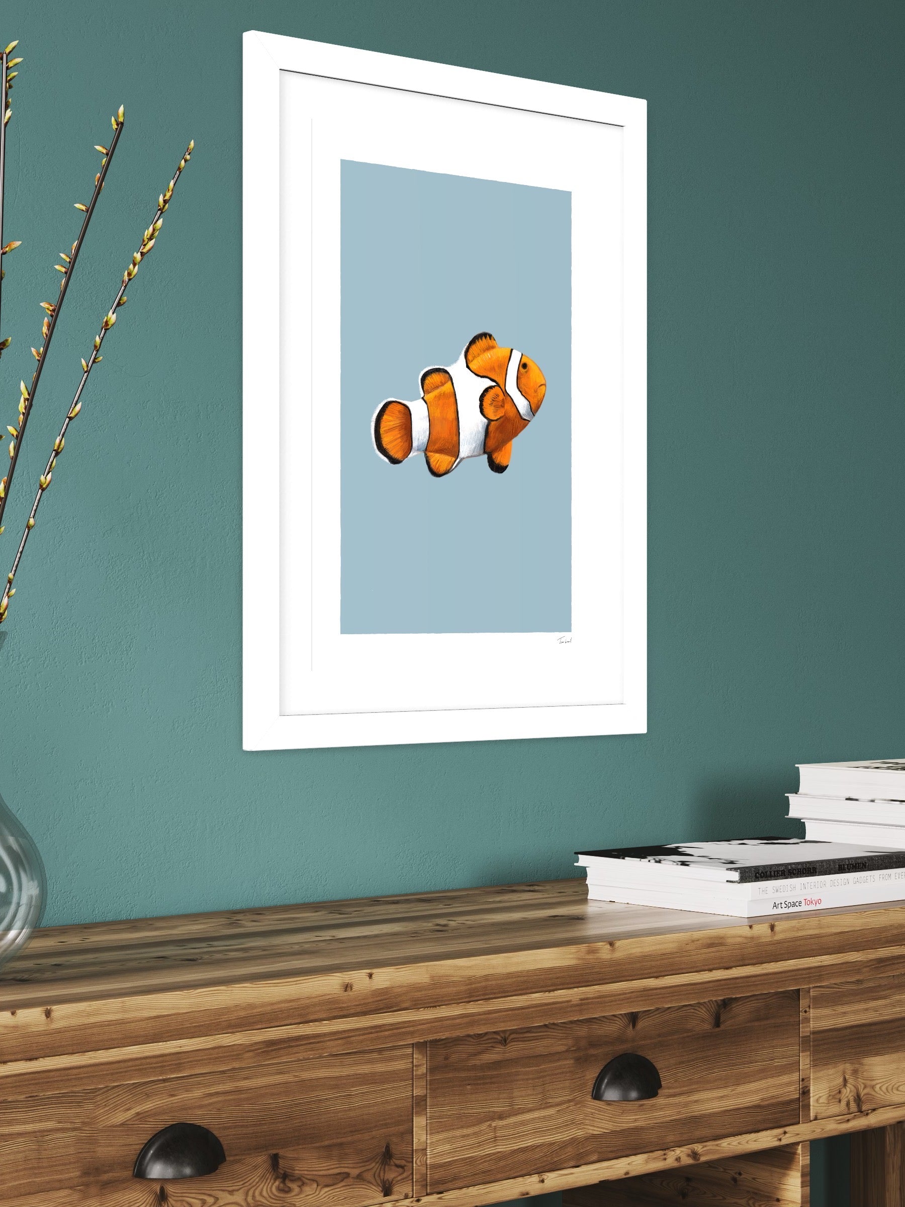This image shows a giclee wall art print by Tom Laird Illustration of an orange and white Clown Fish, framed in a beautiful living room with tasteful modern home decor. This art print is available from Tom Laird Illustration in various sizes.