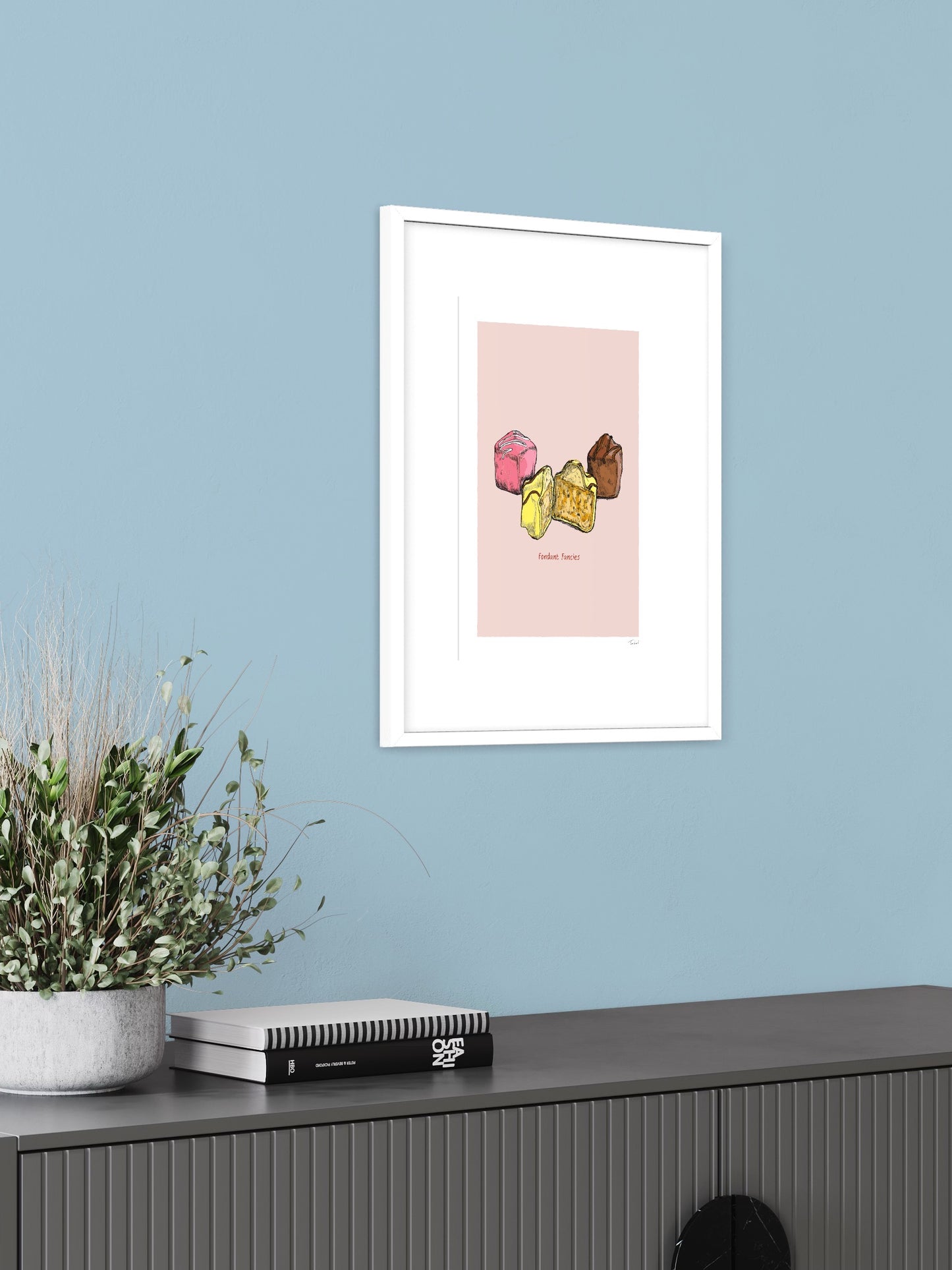 This image shows a giclee wall art print by Tom Laird Illustration of a Fondant Fancies, framed in a beautiful living room with tasteful modern home decor. This art print is available from Tom Laird Illustration in various sizes.