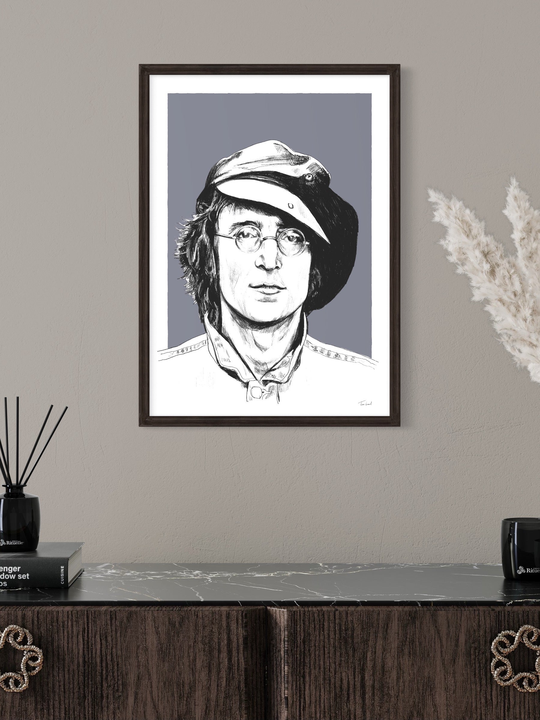 This image shows a giclee wall art print by Tom Laird Illustration of the legendary Beatle John Lennon, framed in a beautiful room with tasteful modern home decor. This art print is available from Tom Laird Illustration in various sizes.