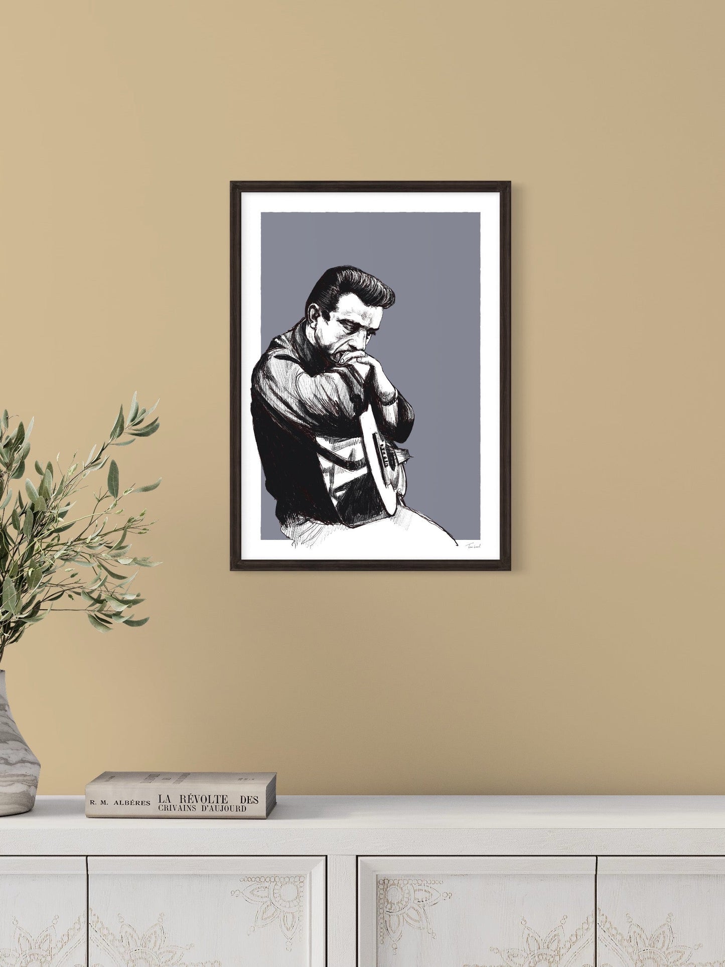 This image shows a giclee wall art print by Tom Laird Illustration of one of the founders or Rock n’ Roll and Country, Johnny Cash, framed in a beautiful room with tasteful modern home decor. This art print is available from Tom Laird Illustration in various sizes.