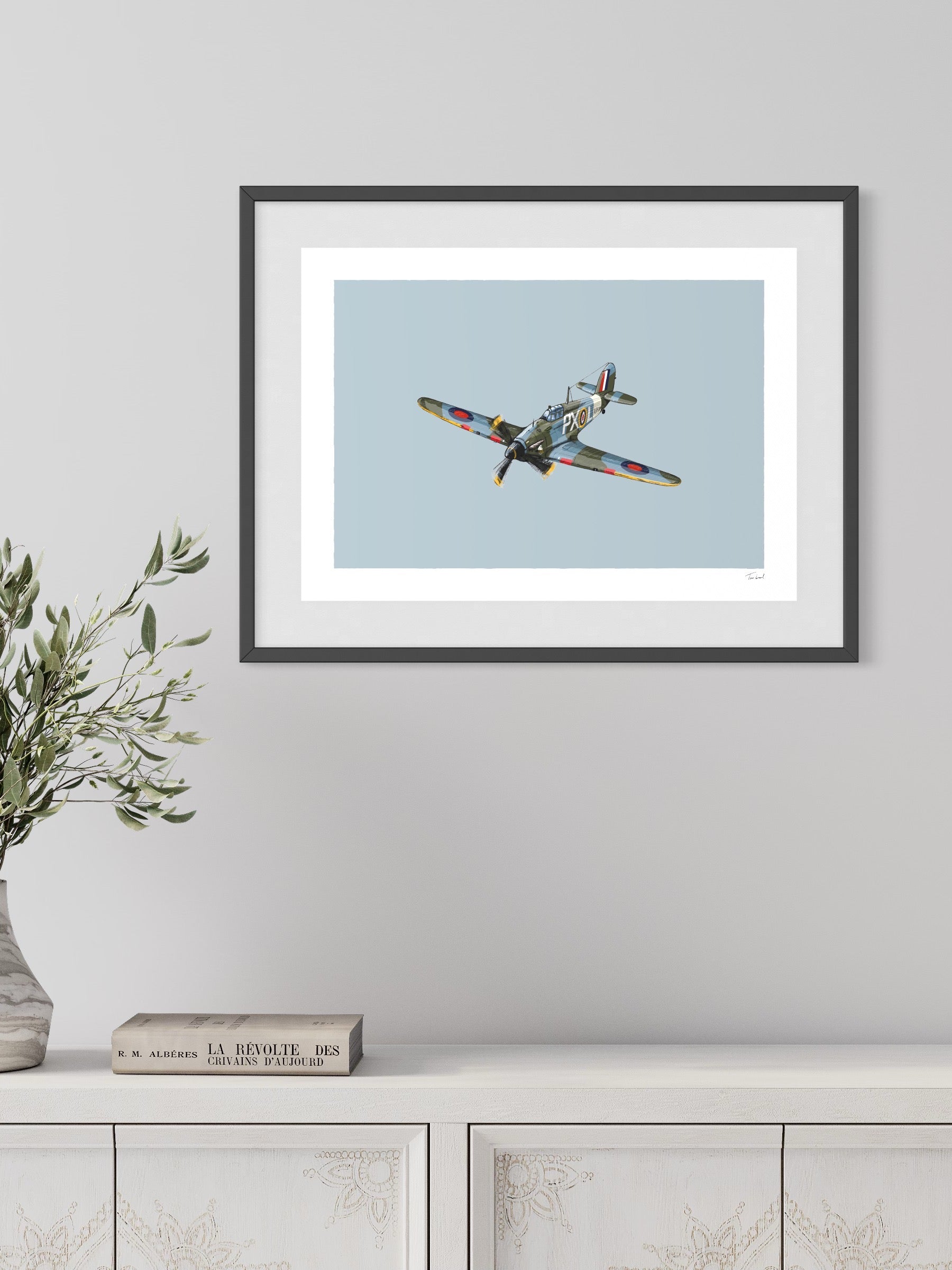 This image shows a giclee wall art print by Tom Laird Illustration of the British classic plane, the Hurricane, framed in a beautiful living room with tasteful modern home decor. This art print is available from Tom Laird Illustration in a variety of sizes.