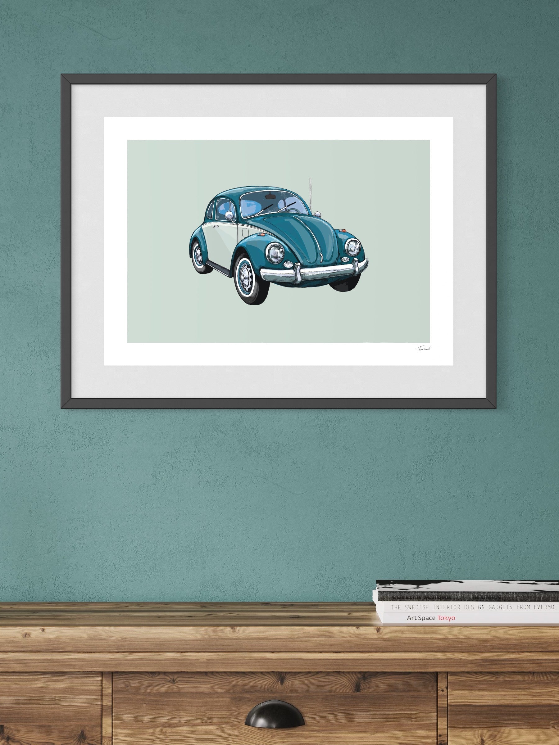 This image shows a giclee wall art print by Tom Laird Illustration of the German classic car, the Volkswagen Beetle, framed in a beautiful living room with tasteful modern home decor. This art print of a turquoise and cream example is available from Tom Laird Illustration in a variety of sizes.