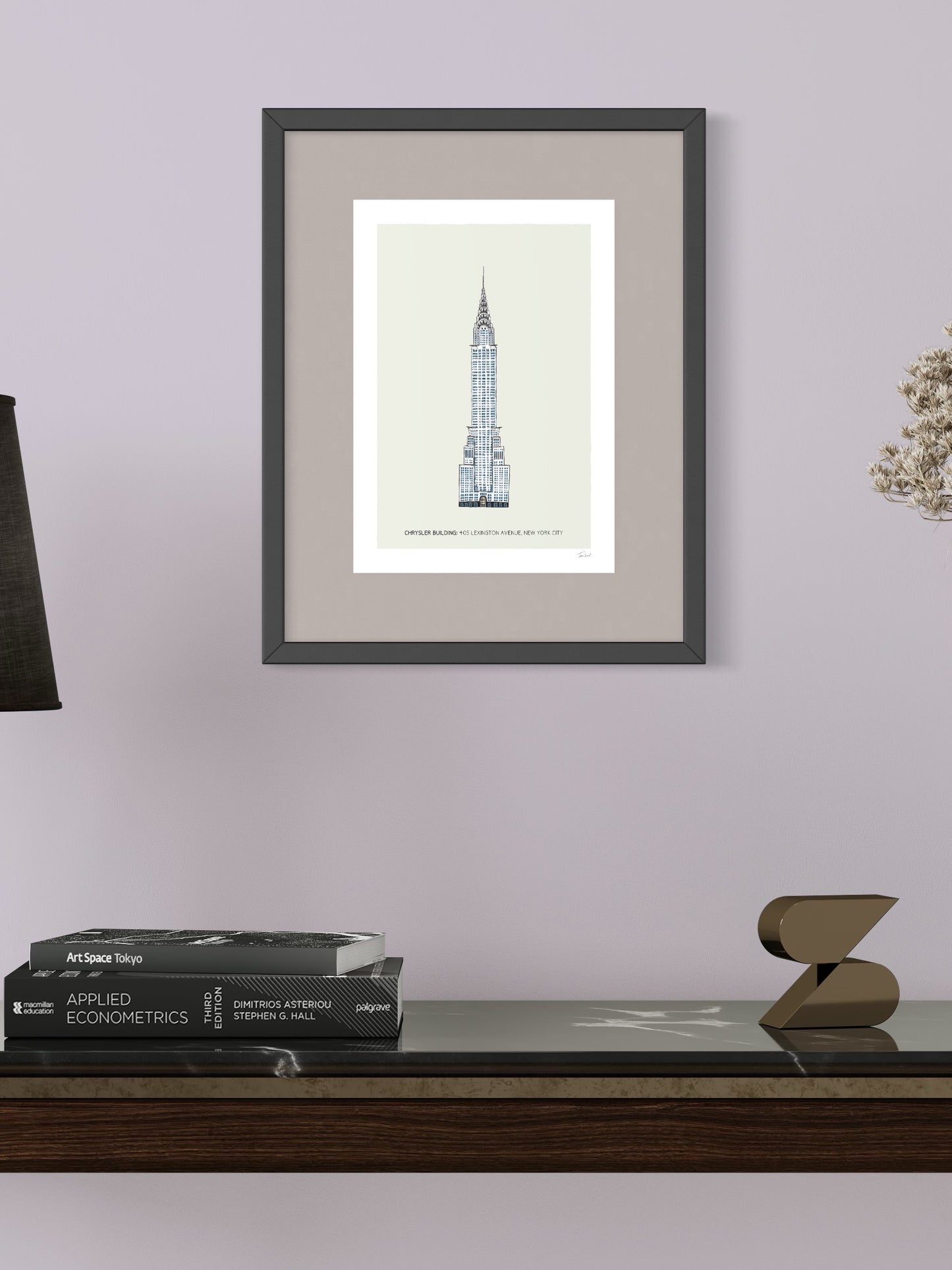 This image shows a giclee wall art print by Tom Laird Illustration of the world-famous New York City landmark the Chrysler Building, framed in a beautiful living room with tasteful modern home decor. This art print is available from Tom Laird Illustration in A4 size.