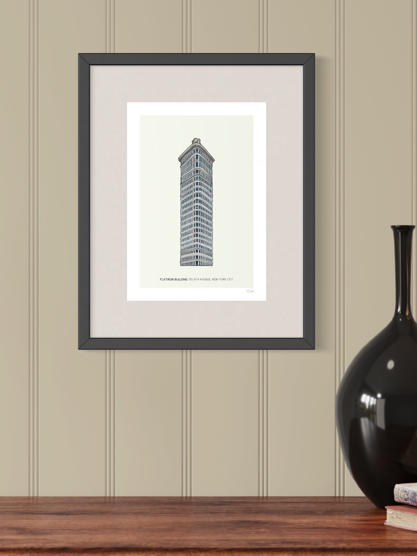 This image shows a giclee wall art print by Tom Laird Illustration of the world-famous New York City landmark the Flatiron Building, framed in a beautiful living room with tasteful modern home decor. This art print is available from Tom Laird Illustration in A4 size.