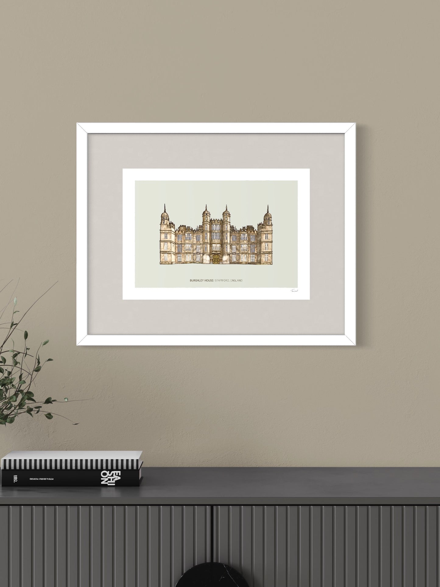 This image shows a giclee wall art print by Tom Laird Illustration of the unique English landmark and home to the world-famous horse trials, Burghley House, near Stamford, framed in a beautiful living room with tasteful modern home decor. This art print is available from Tom Laird Illustration in A4 size.