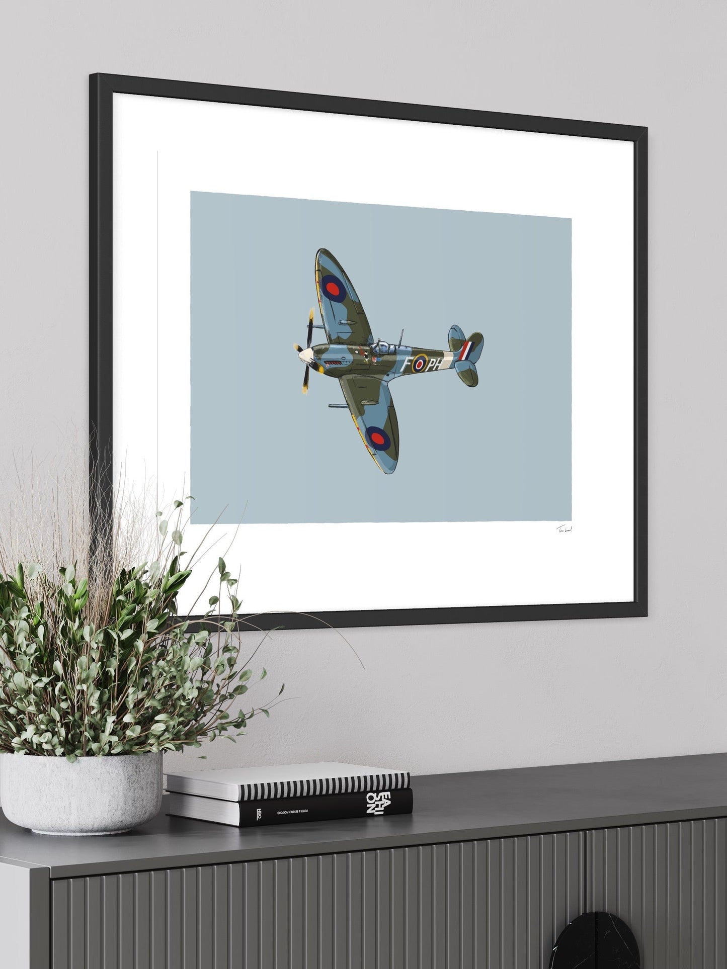 This image shows a giclee wall art print by Tom Laird Illustration of the British classic plane, the Spitfire, framed in a beautiful living room with tasteful modern home decor. This art print is available from Tom Laird Illustration in a variety of sizes.